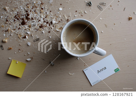 Coffee cup accompanied by scattered crumbs and a name card on a wooden table Coffee cup accompanied by scattered crumbs and a name card on a wooden table 128167921