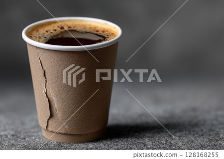 Warm coffee in a textured paper cup set against a neutral background during an afternoon break 128168255