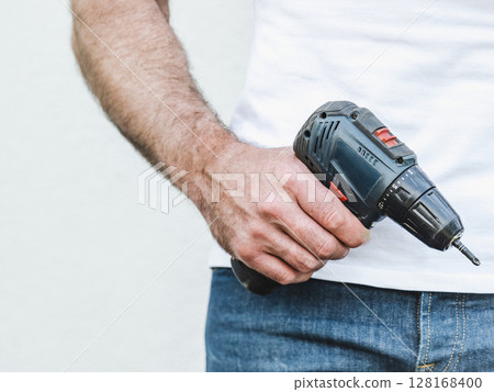 Attractive man, cordless drill and work clothes Attractive man, cordless drill and work clothes 128168400