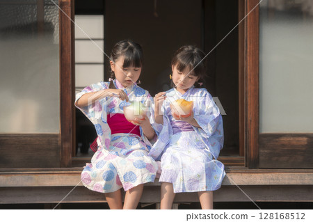 Sisters in yukata eating shaved ice on the veranda 128168512