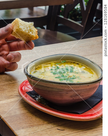 Hot soup in rustic bowl and fresh bread in cozy restaurant setting. High quality photo 128169584