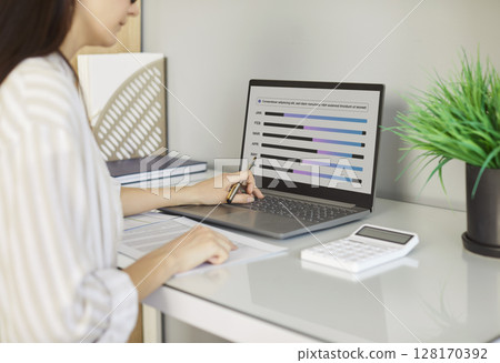 Business woman accountant sitting at the desk with laptop analyzing company finances. 128170392