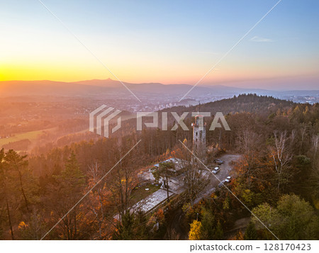 The lookout tower on Prosec Ridge offers a stunning view of Jablonec nad Nisou and the surrounding Jizera Mountains at sunset, illuminating the autumn foliage and tranquil landscape. The lookout tower on Prosec Ridge offers a stunning view of Jablonec nad Nisou and the surrounding Jizera Mountains at sunset, illuminating the autumn foliage and tranquil landscape. 128170423