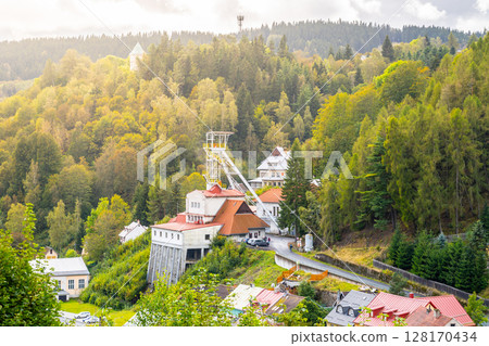 A historic mining tower rises against the backdrop of lush forests in Jachymov, Czechia. The structure reflects the region's rich mining heritage and scenic beauty. 128170434