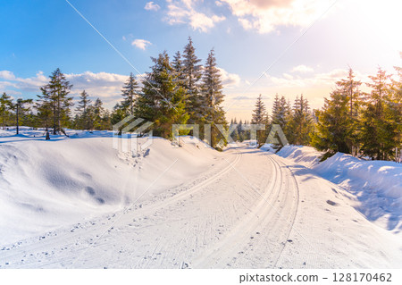 A snow-covered track winds through the scenic Jizera Mountains in Czechia. This winter setting invites cross country skiing enthusiasts to explore the tranquil landscape. 128170462