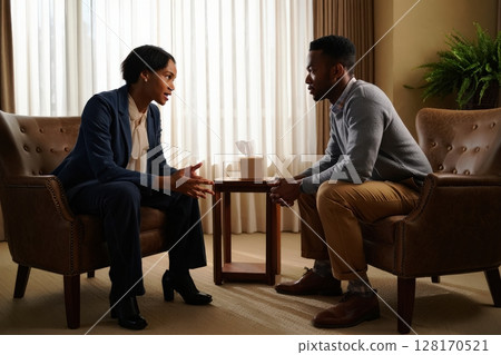 Therapist assisting patient during therapy session in office 128170521