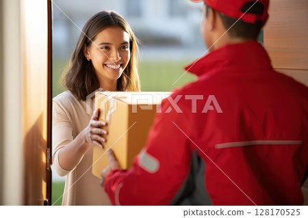Smiling woman receiving package from delivery man at home 128170525