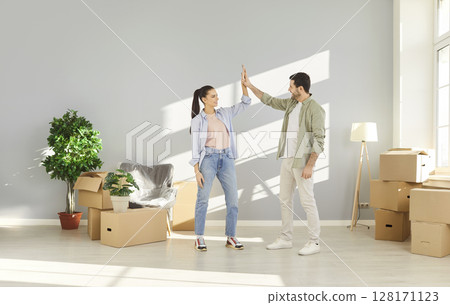 Young couple happy to move to new apartment, gesturing high five as sign of agreement 128171123