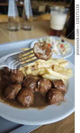 Swedish meatballs with gravy served with French fries and fresh salad on a white plate. This image represents a classic comfort food and traditional dining concept Swedish meatballs with gravy served with French fries and fresh salad on a white plate. This image represents a classic comfort food and traditional dining concept 128171138