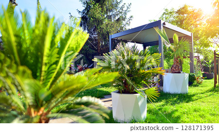Modern aluminum pergola with stylish garden furniture in a beautiful garden. Modern aluminum pergola with stylish garden furniture in a beautiful garden. 128171395