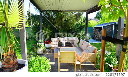 Modern aluminum pergola with stylish garden furniture in a beautiful garden. 128171397