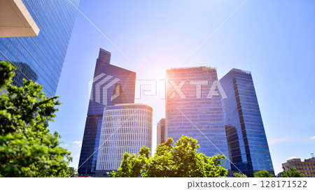 City life, urban landscape and ecology. Modern office complex with glass facades and smooth lines against backdrop of green trees, concept of modern architecture. Organically building into nature. City life, urban landscape and ecology. Modern office complex with glass facades and smooth lines against backdrop of green trees, concept of modern architecture. Organically building into nature. 128171522