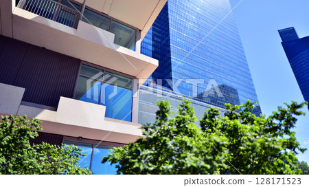 City life, urban landscape and ecology. Modern office complex with glass facades and smooth lines against backdrop of green trees, concept of modern architecture. Organically building into nature. City life, urban landscape and ecology. Modern office complex with glass facades and smooth lines against backdrop of green trees, concept of modern architecture. Organically building into nature. 128171523