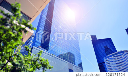 City life, urban landscape and ecology.  Modern office complex with glass facades and smooth lines against backdrop of green trees, concept of modern architecture. Organically building into nature.   128171524