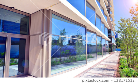 City life, urban landscape and ecology.  Modern office complex with glass facades and smooth lines against backdrop of green trees, concept of modern architecture. Organically building into nature.   128171532
