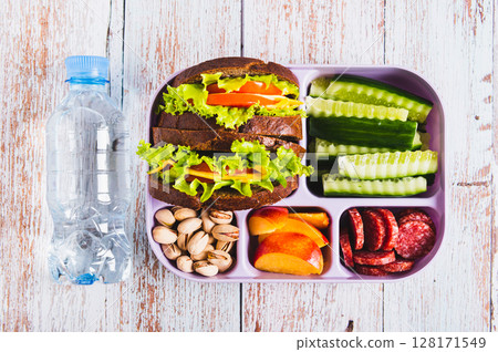 Close up lunch box with food, bottle of water on the table top view Close up lunch box with food, bottle of water on the table top view 128171549
