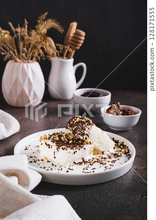 Ice cream sprinkled with chocolate chips and nuts on a plate on the table vertical view 128171555