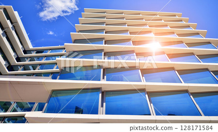 Downtown corporate business district architecture. Glass reflective office buildings against blue sky and sun light. Economy, finances, business activity concept. Abstract modern architecture fragment Downtown corporate business district architecture. Glass reflective office buildings against blue sky and sun light. Economy, finances, business activity concept. Abstract modern architecture fragment 128171584
