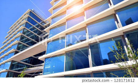 Downtown corporate business district architecture. Glass reflective office buildings against blue sky and sun light. Economy, finances, business activity concept. Abstract modern architecture fragment 128171612