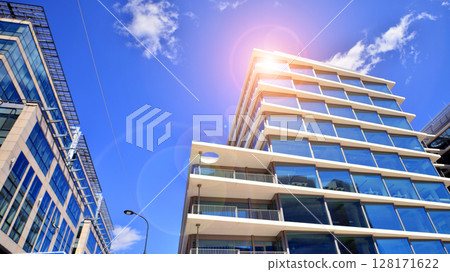 Downtown corporate business district architecture. Glass reflective office buildings against blue sky and sun light. Economy, finances, business activity concept. Abstract modern architecture fragment Downtown corporate business district architecture. Glass reflective office buildings against blue sky and sun light. Economy, finances, business activity concept. Abstract modern architecture fragment 128171622