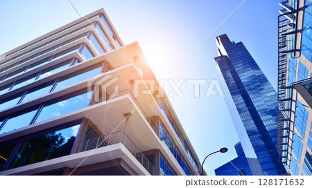 Downtown corporate business district architecture. Glass reflective office buildings against blue sky and sun light. Economy, finances, business activity concept. Abstract modern architecture fragment Downtown corporate business district architecture. Glass reflective office buildings against blue sky and sun light. Economy, finances, business activity concept. Abstract modern architecture fragment 128171632