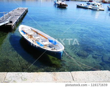 A serene and picturesque view of boats gently floating in the calm waters of the port on Elba Island, Italy. Ideal for conveying relaxation, coastal living, and Italian island life. 128171639