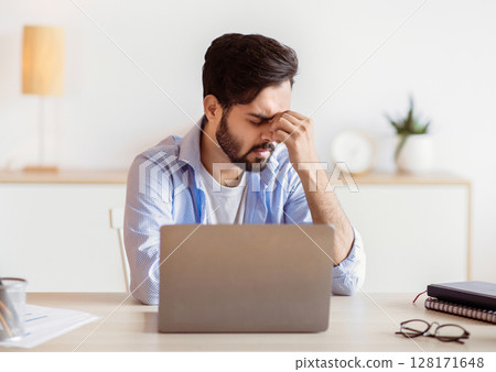 Desperate Eastern Freelancer Guy Sitting At Desk With Laptop, Suffering Lack Of Inspiration Or Feeling Headache, Stressed Young Arab Businessman Having Problems At Work, Free Space Desperate Eastern Freelancer Guy Sitting At Desk With Laptop, Suffering Lack Of Inspiration Or Feeling Headache, Stressed Young Arab Businessman Having Problems At Work, Free Space 128171648