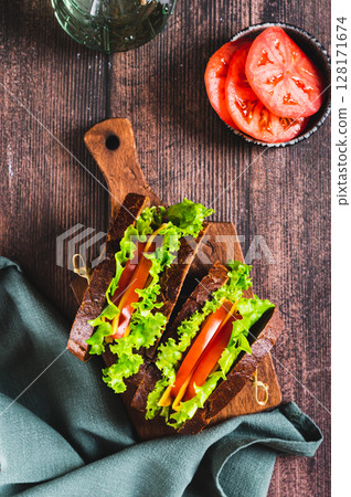 Light sandwich with vegetables and cheese on rye bread on a board top and vertical view 128171674