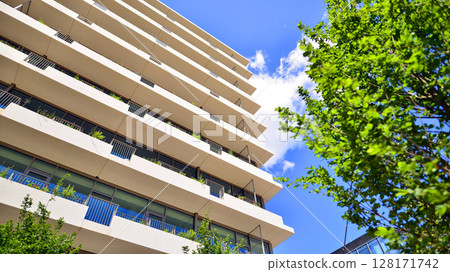 City life, urban landscape and ecology.  Modern office complex with glass facades and smooth lines against backdrop of green trees, concept of modern architecture. Organically building into nature.   City life, urban landscape and ecology.  Modern office complex with glass facades and smooth lines against backdrop of green trees, concept of modern architecture. Organically building into nature.   128171742