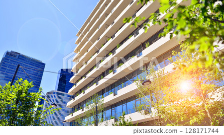 City life, urban landscape and ecology.  Modern office complex with glass facades and smooth lines against backdrop of green trees, concept of modern architecture. Organically building into nature.   City life, urban landscape and ecology.  Modern office complex with glass facades and smooth lines against backdrop of green trees, concept of modern architecture. Organically building into nature.   128171744
