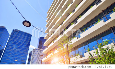 City life, urban landscape and ecology. Modern office complex with glass facades and smooth lines against backdrop of green trees, concept of modern architecture. Organically building into nature. City life, urban landscape and ecology. Modern office complex with glass facades and smooth lines against backdrop of green trees, concept of modern architecture. Organically building into nature. 128171750
