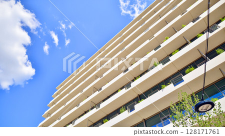 City life, urban landscape and ecology. Modern office complex with glass facades and smooth lines against backdrop of green trees, concept of modern architecture. Organically building into nature. City life, urban landscape and ecology. Modern office complex with glass facades and smooth lines against backdrop of green trees, concept of modern architecture. Organically building into nature. 128171761