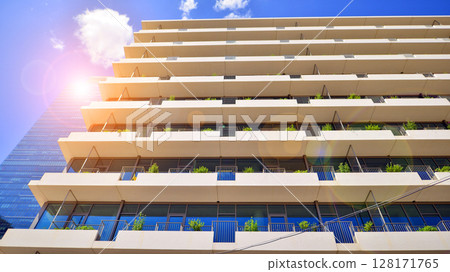 City life, urban landscape and ecology.  Modern office complex with glass facades and smooth lines against backdrop of green trees, concept of modern architecture. Organically building into nature.   128171765