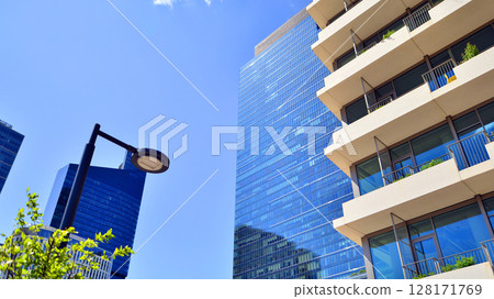 City life, urban landscape and ecology.  Modern office complex with glass facades and smooth lines against backdrop of green trees, concept of modern architecture. Organically building into nature.   128171769