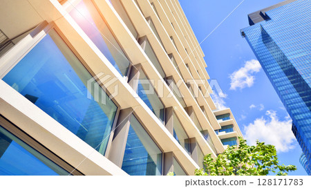 City life, urban landscape and ecology. Modern office complex with glass facades and smooth lines against backdrop of green trees, concept of modern architecture. Organically building into nature. City life, urban landscape and ecology. Modern office complex with glass facades and smooth lines against backdrop of green trees, concept of modern architecture. Organically building into nature. 128171783
