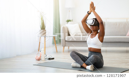 Black Woman Doing Yoga Wearing Virtual Reality Headset Training Sitting On Floor At Home. Smart Fitness, Digital Workout Via Augmented Reality Application Concept. Free Space For Text 128171907