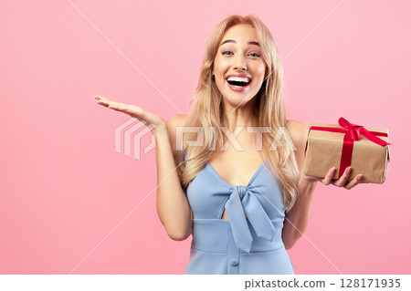 Gifts and presents. Happy Caucasian lady holding wrapped box, feeling excited on pink studio background. Lovely blonde model receiving holiday surprise, celebrating Woman's Day Gifts and presents. Happy Caucasian lady holding wrapped box, feeling excited on pink studio background. Lovely blonde model receiving holiday surprise, celebrating Woman's Day 128171935