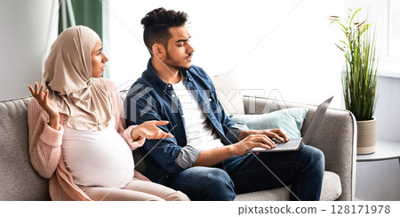 Mood Changes During Pregnancy. Annoyed pregnant muslim woman looking at husband that spending time with laptop and ignoring wife, middle eastern family suffering conflicts while awaiting baby 128171978