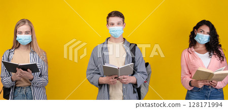 Education and social distance at school, college and university during covid. Young latin and european students in protective masks read books, isolated on orange background, studio shot, empty space Education and social distance at school, college and university during covid. Young latin and european students in protective masks read books, isolated on orange background, studio shot, empty space 128171994