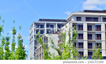 European residential architecture harmonizing with nature. Eco-friendly living in city with greens. Eco apartment building saving energy and fresh air concept.  128172169