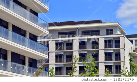 European residential architecture harmonizing with nature. Eco-friendly living in city with greens. Eco apartment building saving energy and fresh air concept.  128172179