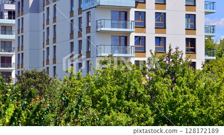 European residential architecture harmonizing with nature. Eco-friendly living in city with greens. Eco apartment building saving energy and fresh air concept.  128172189