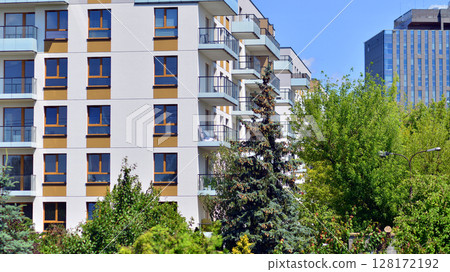 European residential architecture harmonizing with nature. Eco-friendly living in city with greens. Eco apartment building saving energy and fresh air concept.  128172192