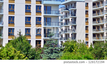 European residential architecture harmonizing with nature. Eco-friendly living in city with greens. Eco apartment building saving energy and fresh air concept. European residential architecture harmonizing with nature. Eco-friendly living in city with greens. Eco apartment building saving energy and fresh air concept. 128172194