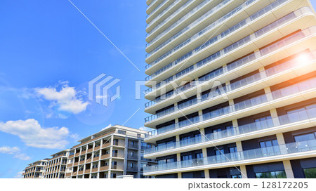 Exterior of a high modern multi-story apartment building - facade, windows and balconies. Modern glass balcony railings. Exterior of a high modern multi-story apartment building - facade, windows and balconies. Modern glass balcony railings. 128172205