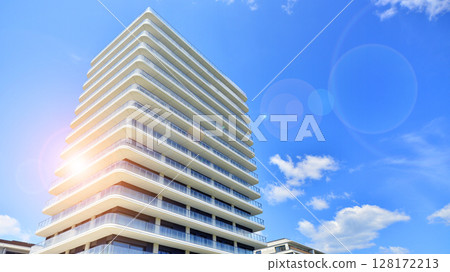 Exterior of a high modern multi-story apartment building - facade, windows and balconies. Modern glass balcony railings. Exterior of a high modern multi-story apartment building - facade, windows and balconies. Modern glass balcony railings. 128172213