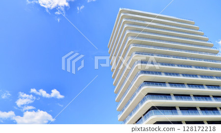 Exterior of a high modern multi-story apartment building - facade, windows and balconies. Modern glass balcony railings. 128172218