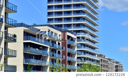Exterior of a high modern multi-story apartment building - facade, windows and balconies. Modern glass balcony railings. Exterior of a high modern multi-story apartment building - facade, windows and balconies. Modern glass balcony railings. 128172226