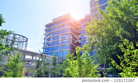 Sustainable glass office building with trees for reducing carbon dioxide. Eco-friendly building in modern city. Office with green environment. Corporate building reduce CO2. 128172267