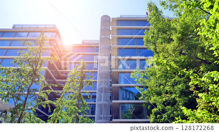 Sustainable glass office building with trees for reducing carbon dioxide. Eco-friendly building in modern city. Office with green environment. Corporate building reduce CO2. 128172268